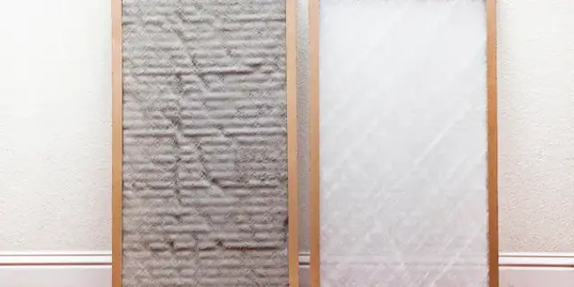 Two air filters side by side; the left filter is gray and covered in dirt, possibly indicating mold, while the right filter is clean and white. Both have wooden frames and are leaning against a light-colored wall.