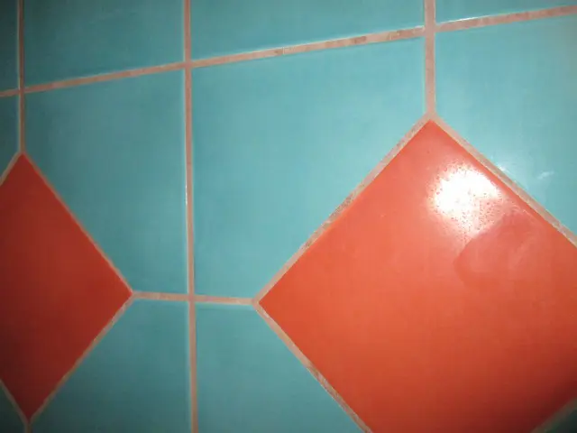 A wall with a geometric pattern of turquoise square tiles and larger orange diamond-shaped tiles stands out. The surface, having passed meticulous inspection, appears smooth and glossy, subtly reflecting light.