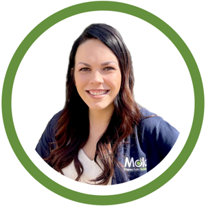 A woman with long dark hair smiling, wearing a black jacket over a light top, stands centered within a green circular border. The jacket has a Mold Inspection Sciences logo. Her confident gaze reflects thorough assessment skills. The background is white.