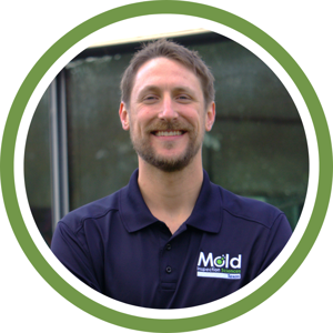 A smiling person with short hair wears a dark blue collared shirt featuring a Mold Inspection Sciences Texas logo, standing against an outdoor backdrop. The image, framed in a green-bordered circular shape, captures their professional aura ready for mold assessment.