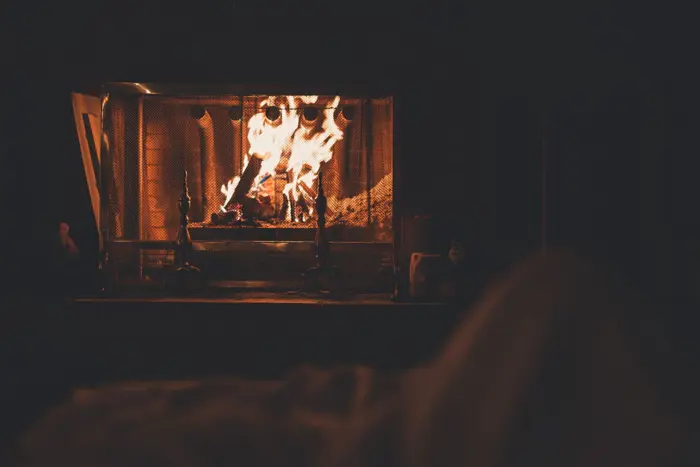 A cozy fireplace emits warm, flickering flames in a dimly lit room, setting the perfect backdrop for an impromptu inspection of life's simple pleasures.