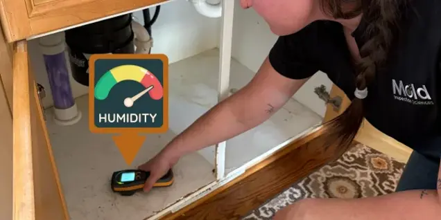 A person uses a handheld humidity meter under a kitchen sink for mold testing. A graphic showing a high humidity gauge and the word Humidity is overlaid on the image.