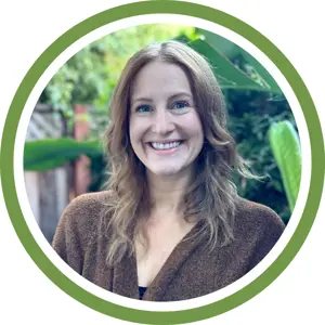 A woman with light brown hair and a brown sweater smiles at the camera, standing outdoors with green plants in the background, framed by a green and white circular border—perfect for your next assessment or inspection project.