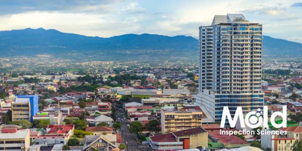 A cityscape showcases a tall, modern building amidst smaller structures and houses. Mountains loom in the distance under a partly cloudy sky. The words Mold Inspection Sciences preside in the lower right corner, highlighting a thorough inspection of urban elegance and natural beauty.