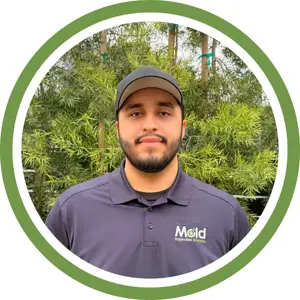 A man wearing a black cap and a dark polo shirt with a Mold Inspection Sciences logo stands in front of green foliage, framed by a green and white circular border—ready for mold assessment or investigation.
