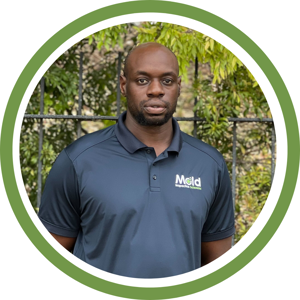 A man, wearing a navy polo shirt with a company logo, is pictured against a backdrop of green foliage. The image, framed by a green circular border, captures the essence of careful sampling in nature's laboratory.