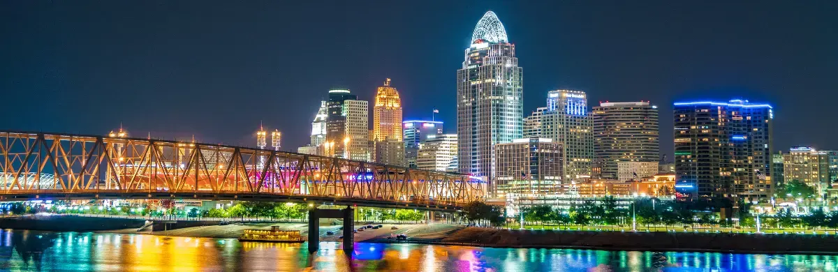 Night view of a city skyline with illuminated skyscrapers and a lit bridge reflecting on the water below, the scene offering a breathtaking visual assessment that captivates all who witness its magnificence.