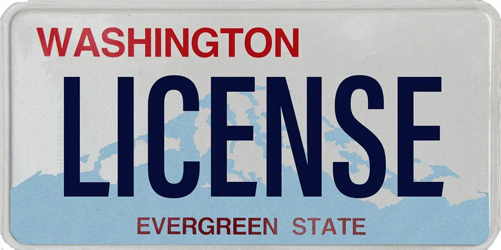 A Washington state license plate displays the word LICENSE in bold blue letters. WASHINGTON is elegantly printed in red above, with EVERGREEN STATE subtly showcased below. The backdrop features a light blue outline of a mountain, offering a sampling of the state's natural beauty.