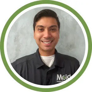 A smiling man with dark hair wearing a dark polo shirt with a Mold Inspection logo, posed in front of a light textured background and framed by a green circular border, ready for your next inspection or assessment.